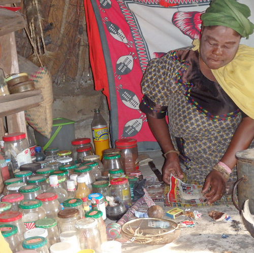 Doctor Mbuyazi is folding medicinal powder into a newspaper envelope.